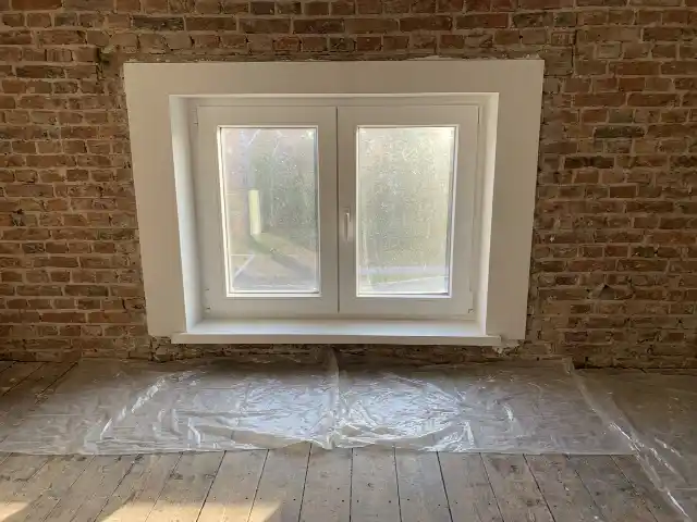 Châssis PVC fraîchement posé dans un séjour, bâches encore au sol